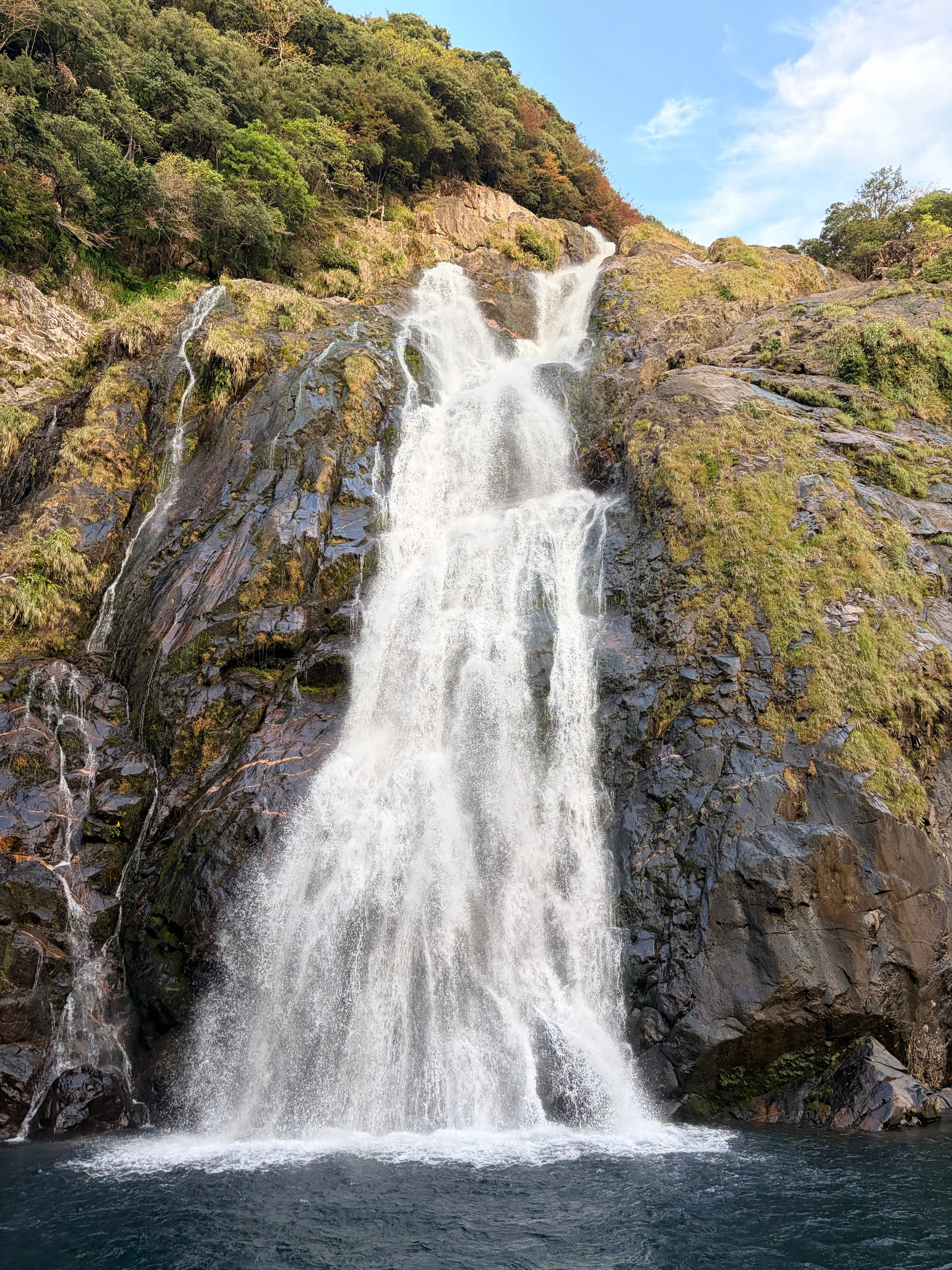 岩肌に沿って広がる白い水流と大川の滝の滝壺
